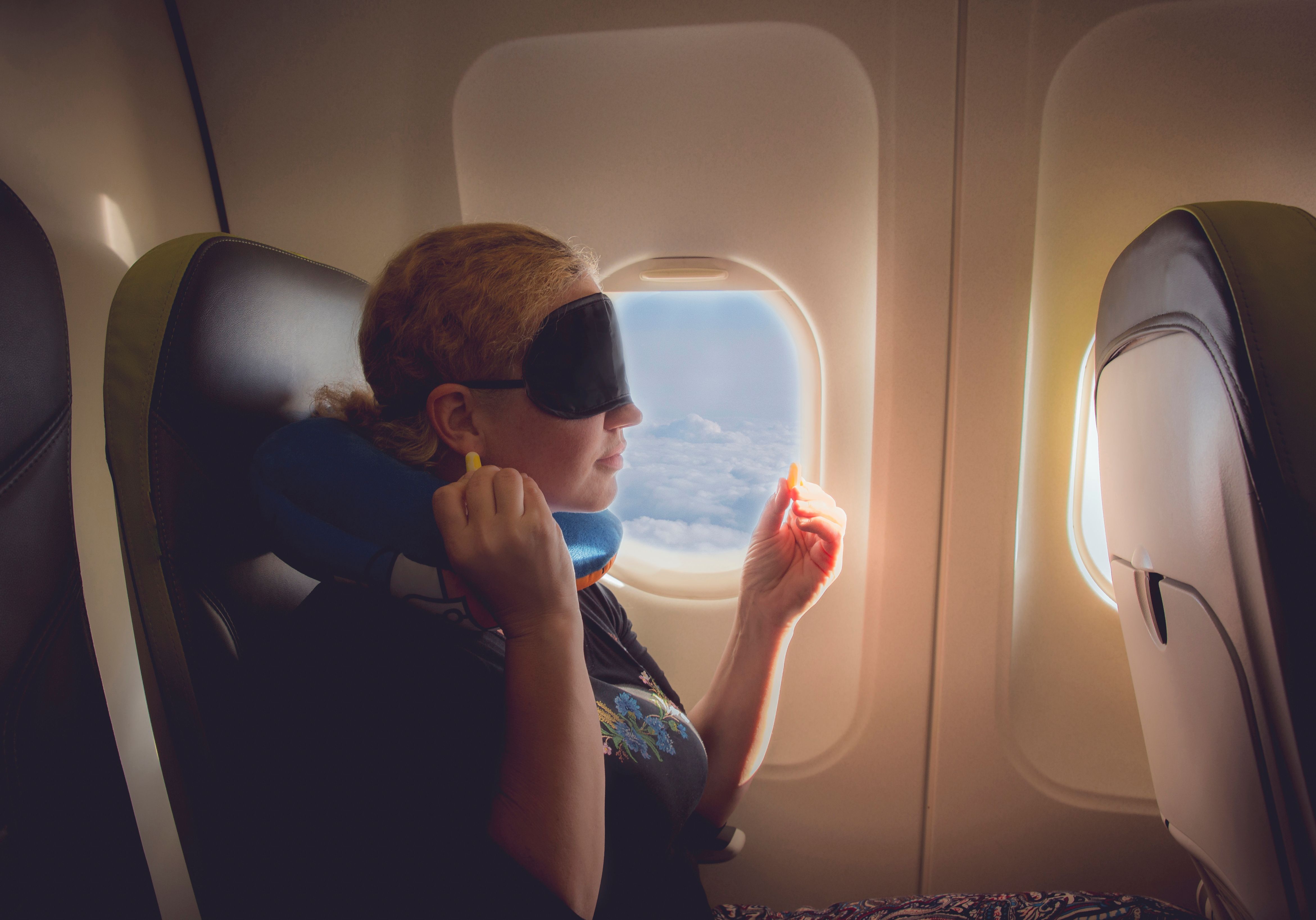um passageiro de avião com uma máscara para os olhos e tampões para os ouvidos