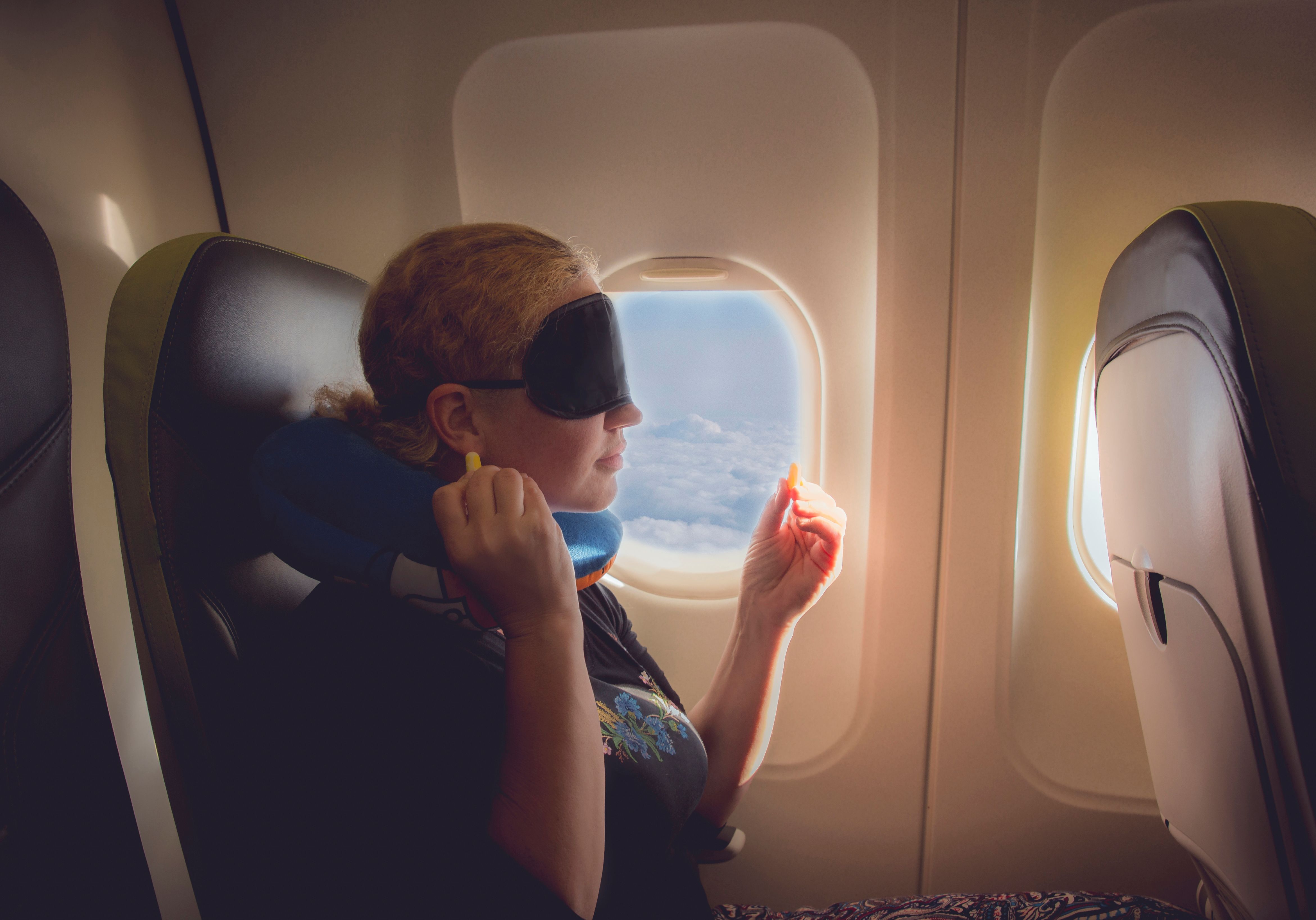 Se já faz um tempo desde que você esteve em um avião, essas dicas anti-ansiedade devem ajudar 3 um passageiro de avião com uma máscara para os olhos e tampões para os ouvidos