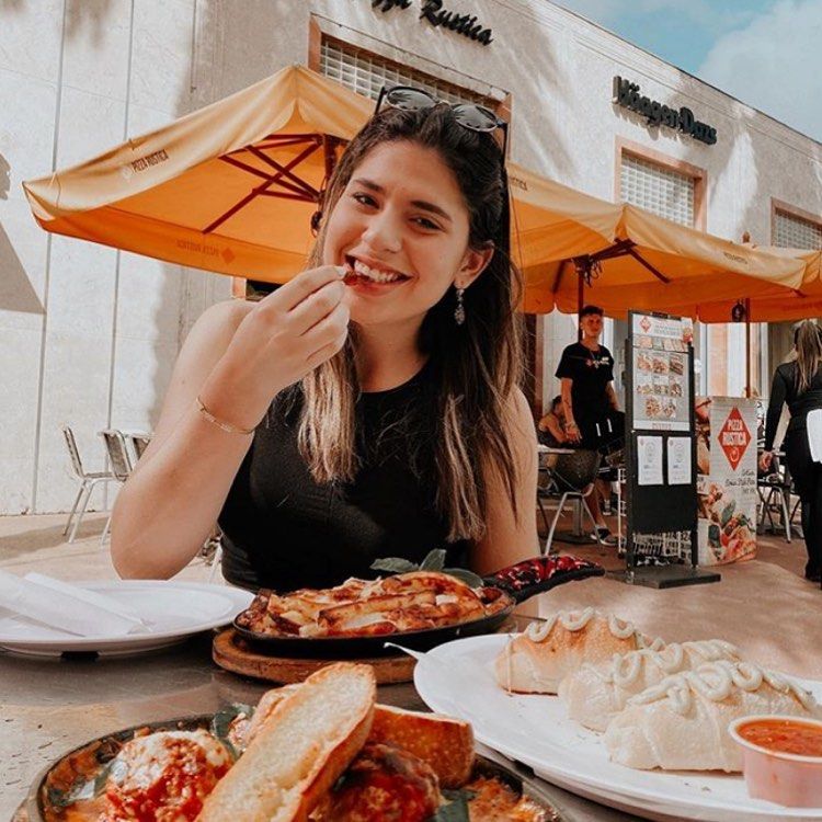Mulher comendo ao ar livre no Miami's Pizza Rustica