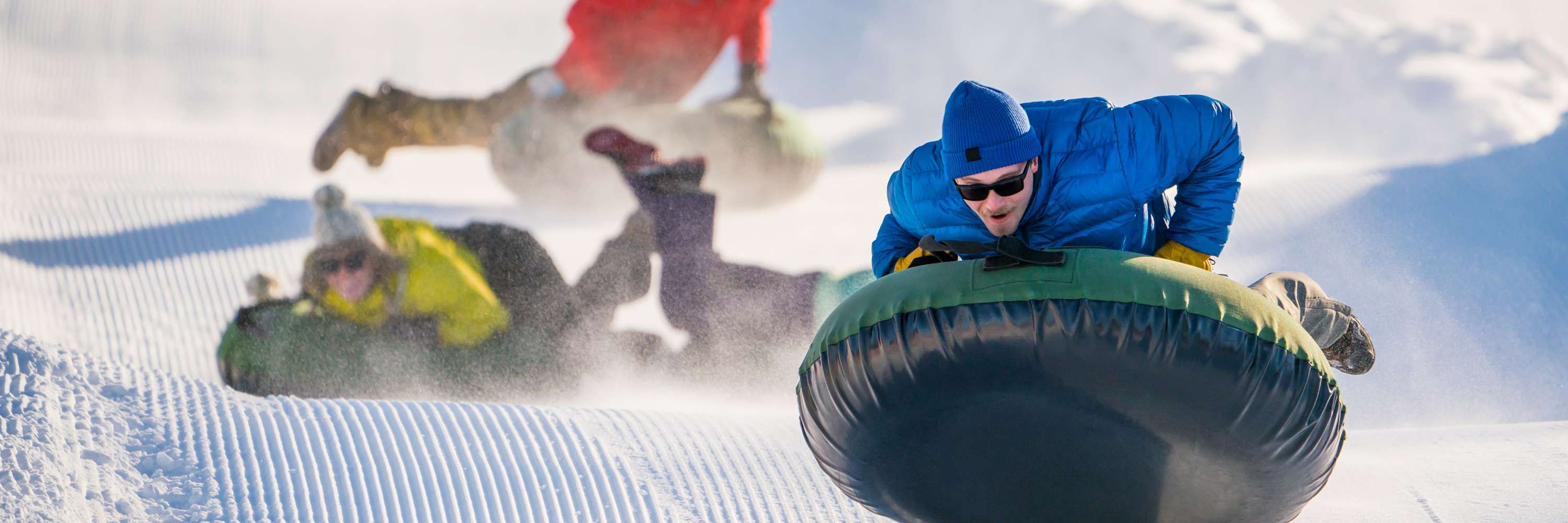 Querendo saber o que você pode fazer no inverno? Adicione estas atividades recreativas à sua lista 4 pessoas indo de snow tubing