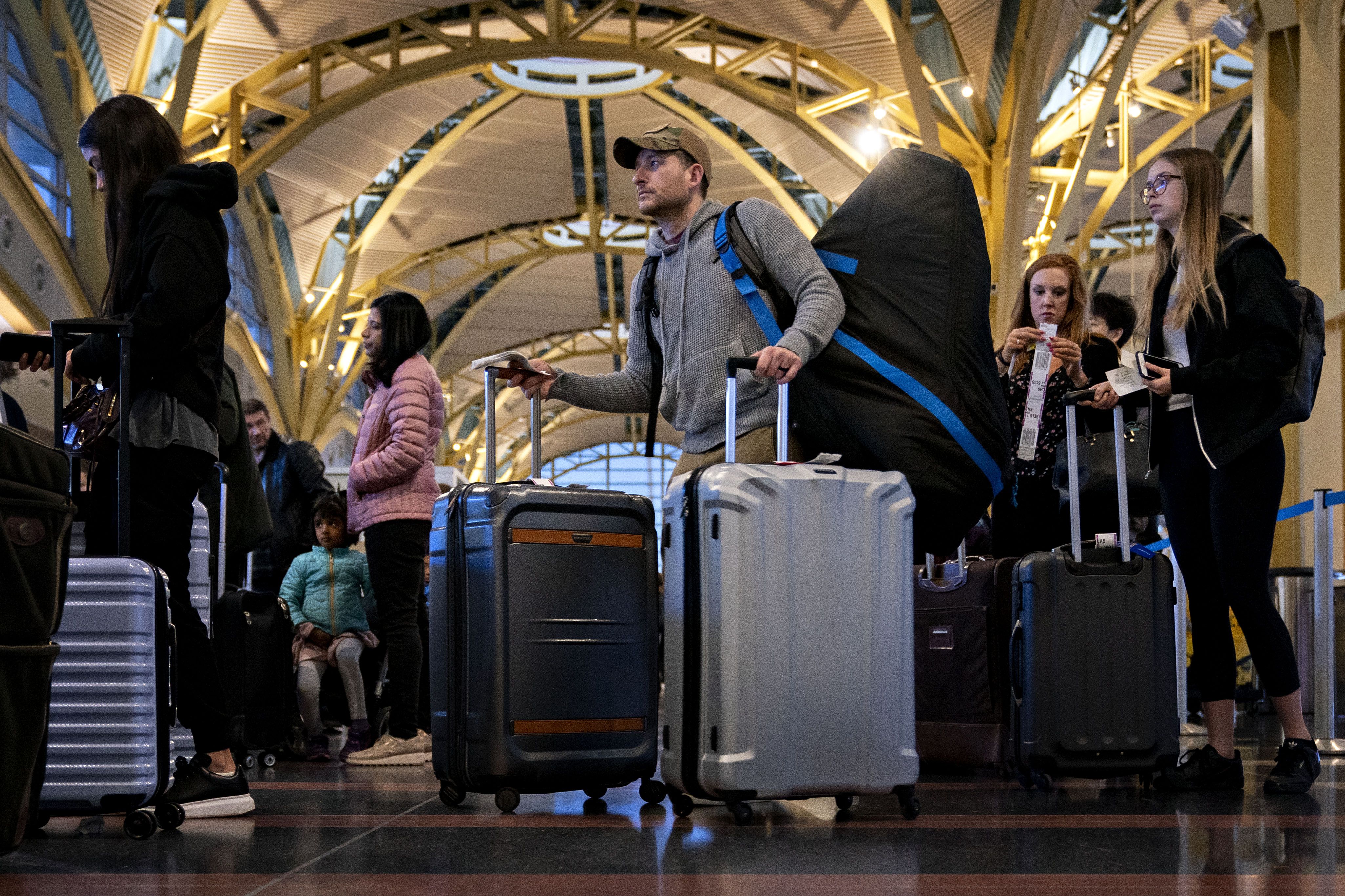 Estas são as taxas extras que as companhias aéreas adicionam à sua tarifa (e como evitar esses custos) 2 Fila de passageiros com bagagem esperando para embarcar