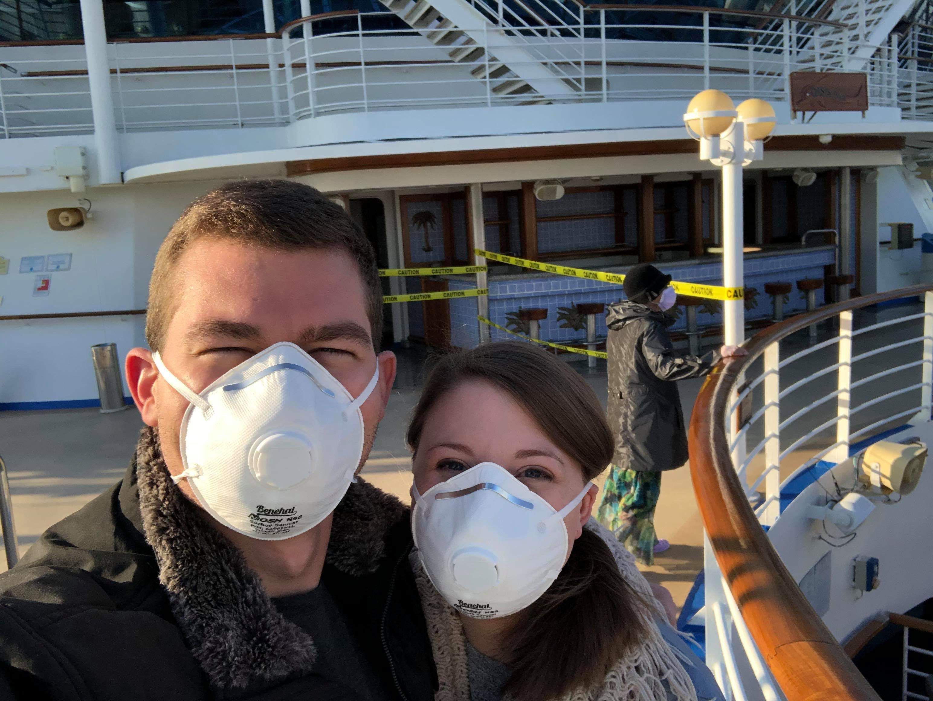pessoas usando máscaras na frente do navio de cruzeiro